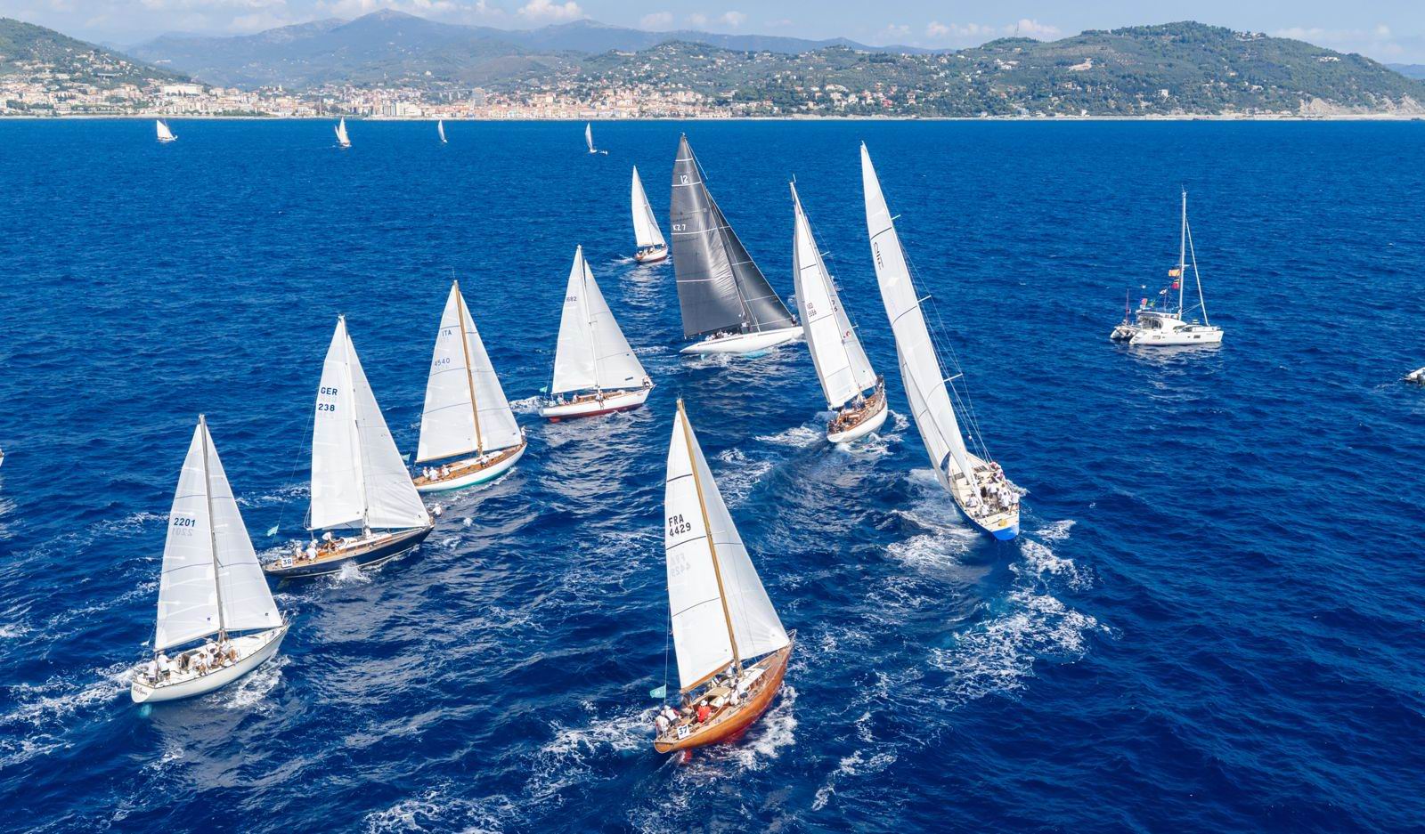 Imperia, 3 settembre 2026. L'estate resta accanto alle barche d'epoca e regala alla flotta un'altra giornata di brezza da Levante e sole, in cui si è svolta la seconda regata costiera di questa edizione. Dopo la boa di disimpegno al vento, la flotta si è diretta verso Sud con uno spettacolare lato al lasco, visibile anche dalle spiagge, per poi affrontare il traversino che le ha condotte alla linea d'arrivo, posta davanti al porto di Imperia